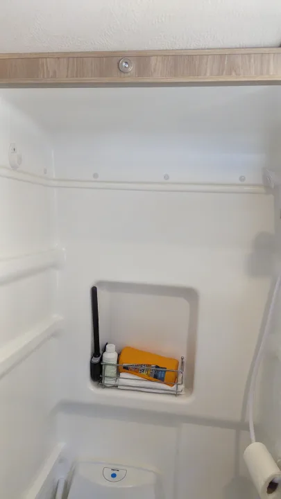 Compact RV rental wet bath with toilet, shower, and toiletries shelf.. Winnebago Solis 59PX 2023