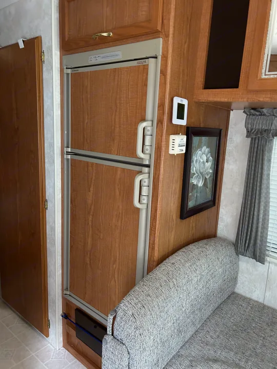 RV rental living area featuring a Dometic Americana refrigerator, comfortable sofa, and practical wall controls.. Coachmen Catalina 2003