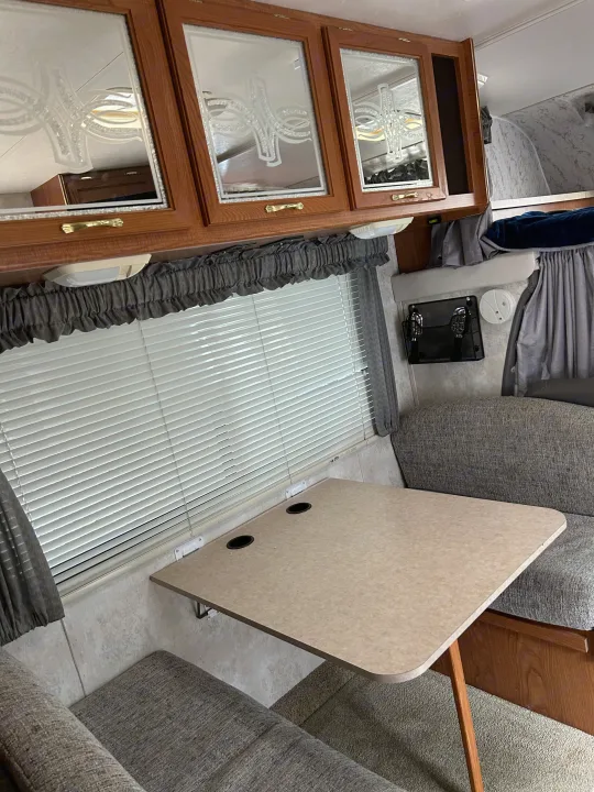 Step inside this RV rental! Features a comfortable dinette with a table, padded seating, and ample storage cabinets.. Coachmen Catalina 2003