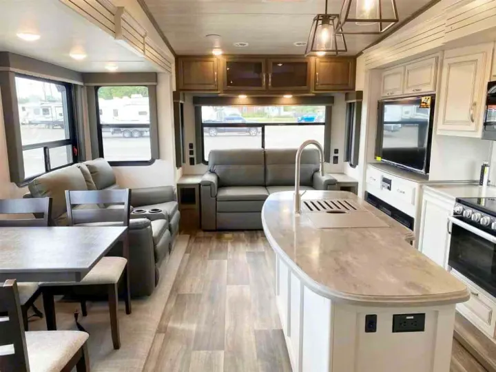 Modern, spacious rv rental interior. Features living area sofas, dining table, and kitchen island with sink and appliances.. Keystone Cougar 2022