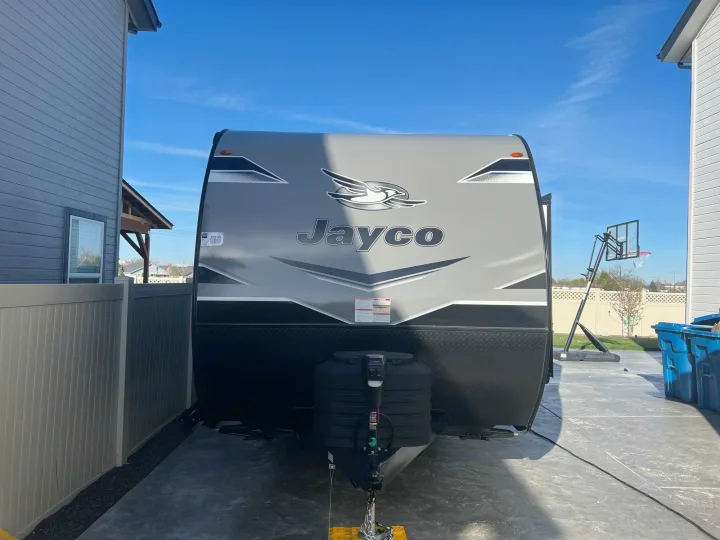 Grey Jayco travel trailer parked in a driveway under a blue sky, ready for an RV rental adventure.. Jayco Jayflight 2024