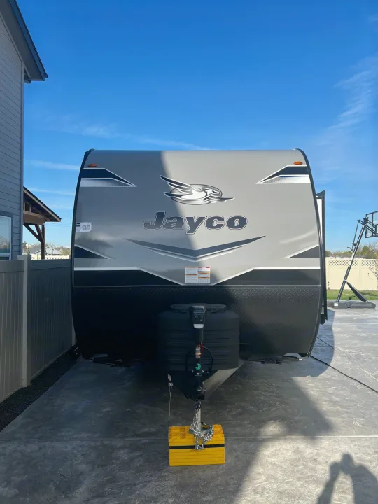 Front view of a parked gray and black Jayco travel trailer, perfect for an rv rental getaway. Bright sky, concrete pad.. Jayco Jayflight 2024