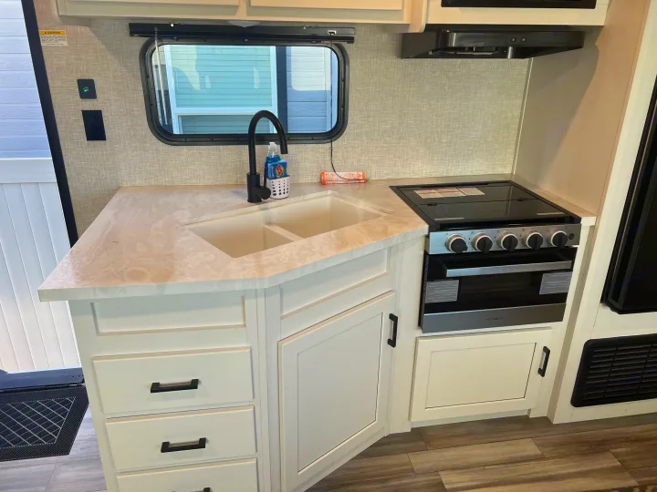 Explore this RV rental's modern kitchen with a dual sink, stove/oven, and light wood-look cabinets & flooring.. Jayco Jayflight 2024