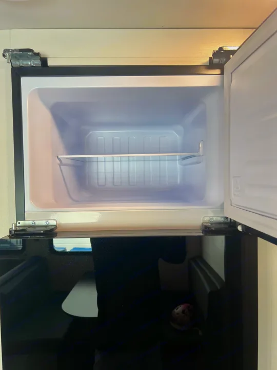 Open, empty mini-fridge inside an rv rental, ready for your travel snacks and drinks. Compact interior shown.. Jayco Jayflight 2024