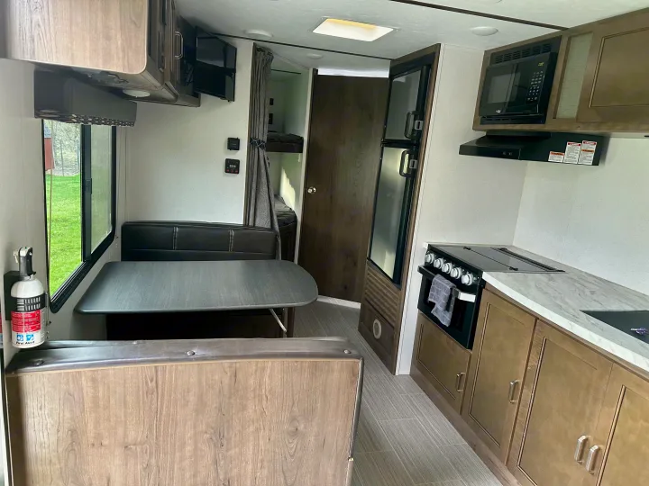 Modern RV rental interior featuring a bright kitchen, cozy dinette with window views, and bunk beds for family comfort.. Keystone RV Passport Express 2019