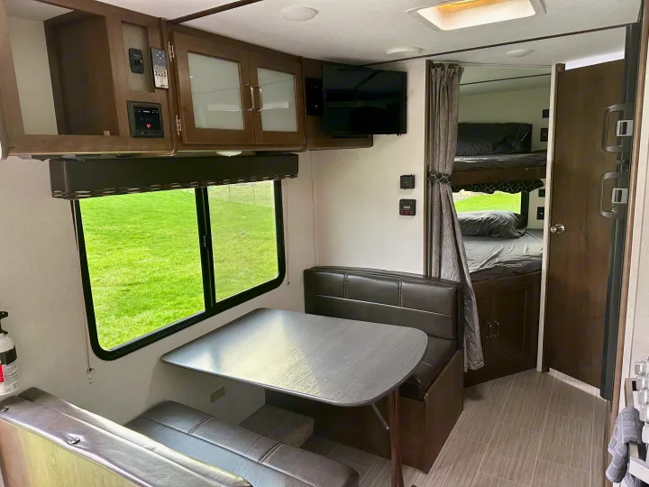 RV rental interior: cozy dinette, modern cabinets, integrated entertainment, and bunk beds. Ideal for your next family adventure.. Keystone RV Passport Express 2019