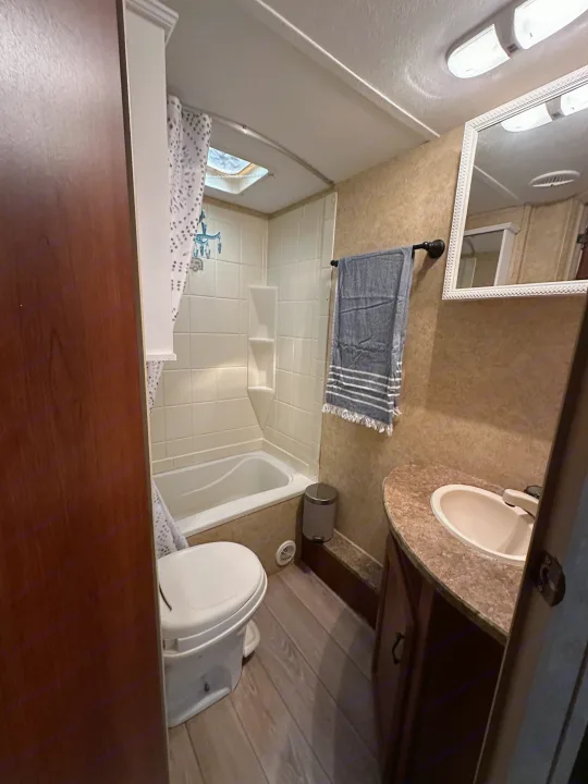 Compact RV rental bathroom featuring a shower/tub, toilet, and vanity with a sink and mirror. Perfect for travel.. Forest River Tracer Executive 2010