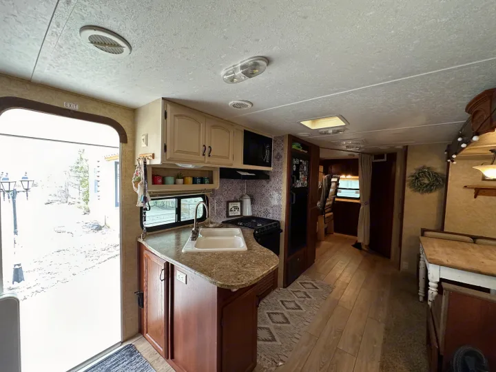 Cozy RV rental kitchen featuring a sink, stove, and cabinets, with a snowy outdoor view. Ideal for a comfortable stay.. Forest River Tracer Executive 2010