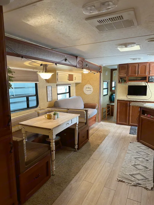 Spacious RV rental interior featuring a cozy dining area, sofa, and partial kitchen, designed for comfortable travel.. Forest River Tracer Executive 2010
