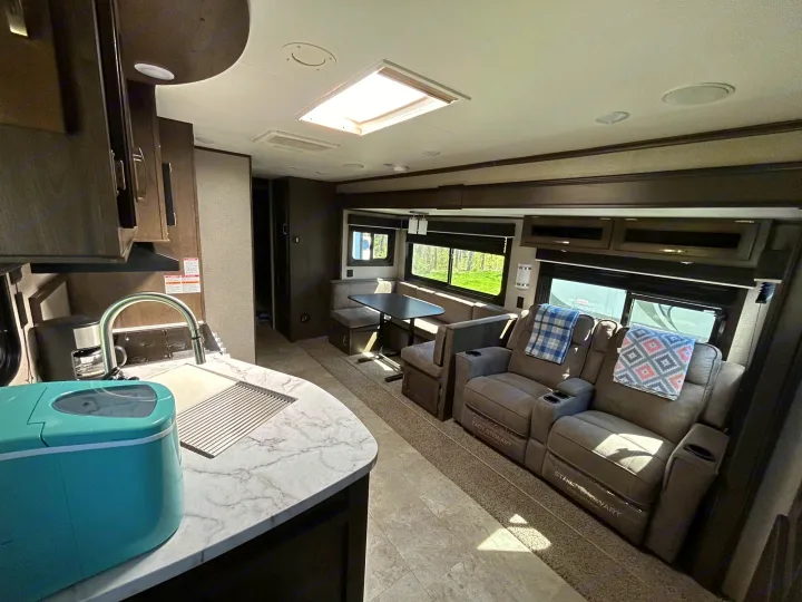 Inside a modern RV rental: kitchen with ice maker, dining booth, and comfy recliners, ready for your adventure.. Jayco Jay Flight 2020