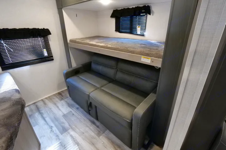 RV rental interior: bunk bed over a sofa sleeper, with windows, blinds, and light wood-look flooring.. Dutchmen Coleman Light 2022