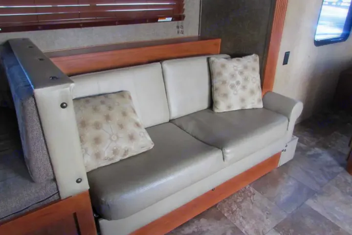 Relax in this RV rental's comfy sleeper sofa with decorative pillows, perfect for a cozy road trip.. Forest River Cherokee Grey Wolf 2014