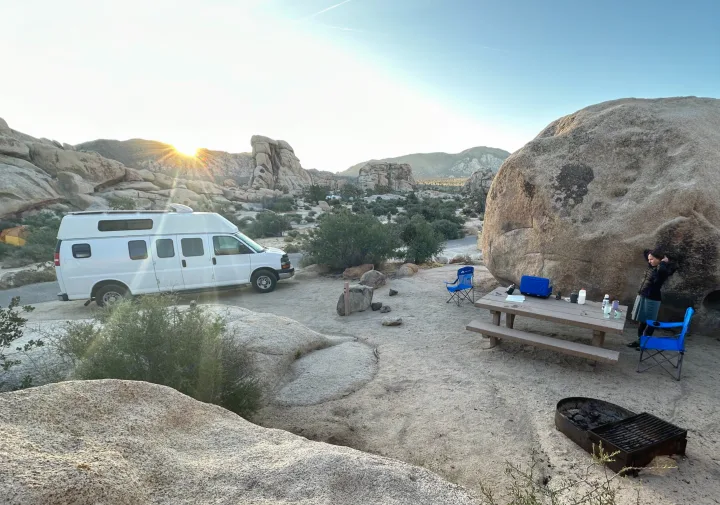 Discover peace at this desert campsite with an RV rental, picnic setup, and stunning rock views during sunrise.. Chevrolet Express EXT 3500 2008