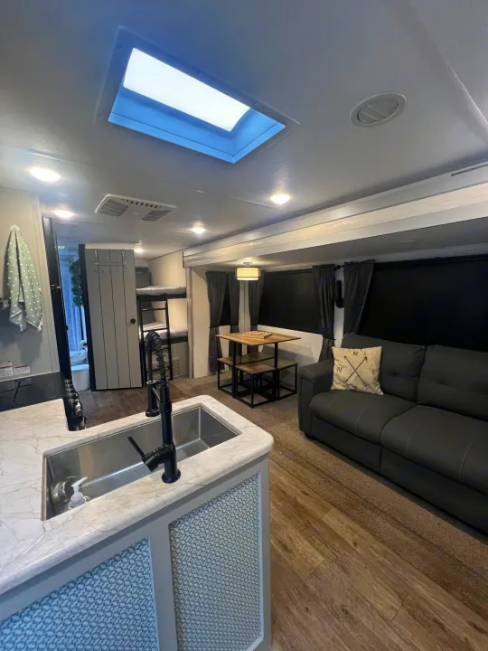 Step into this modern RV rental! Features an open kitchen, comfy sofa, dining, and bunk beds with bright skylight.. Forest River Vibe 2021