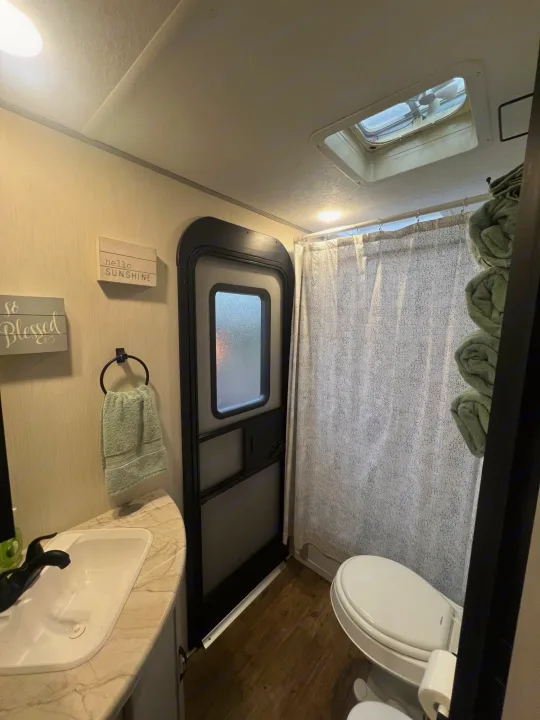 RV rental bathroom features sink, toilet, and shower with curtain; designed for compact, comfortable travel.. Forest River Vibe 2021