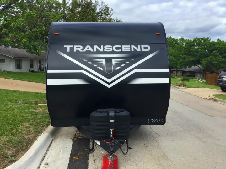 Front view of a black Transcend travel trailer, ideal for an RV rental. Shows its modern design and front hitch setup.. Grand Design Transcend Xplor 2024