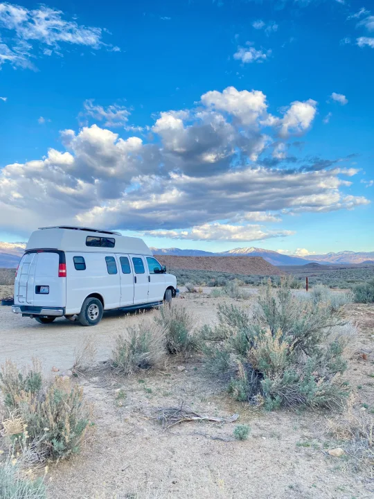 White RV rental parked in a scenic desert landscape with snow-capped mountains under a partly cloudy blue sky.. Chevrolet Express EXT 3500 2008