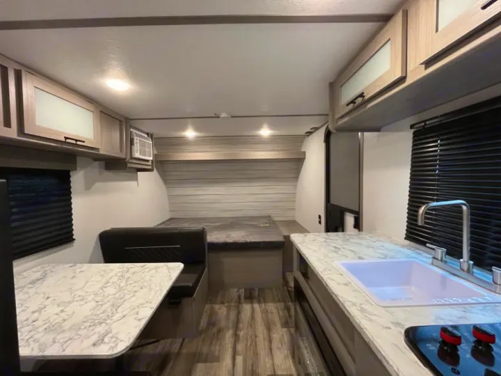 This rv rental offers a modern interior with a well-equipped kitchen, dining booth, and rear bed for travelers.. Coleman Lantern LT 17 B 2024
