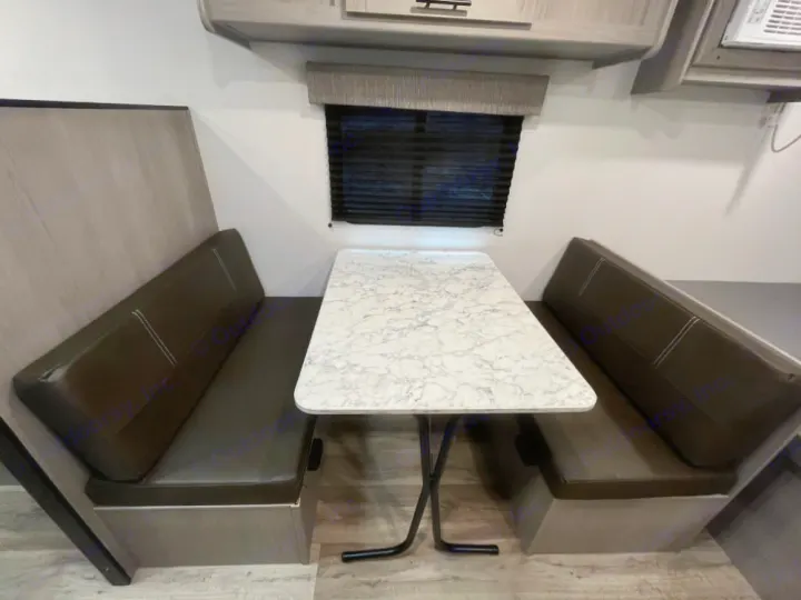 RV rental dinette with comfortable dark benches, a white marble-look table, and window blinds.. Coleman Lantern LT 17 B 2024