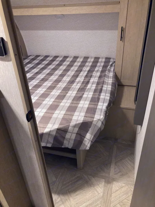 Cozy RV rental bedroom with plaid bedding and integrated storage.. Forest River Salem Cruise Lite 2023