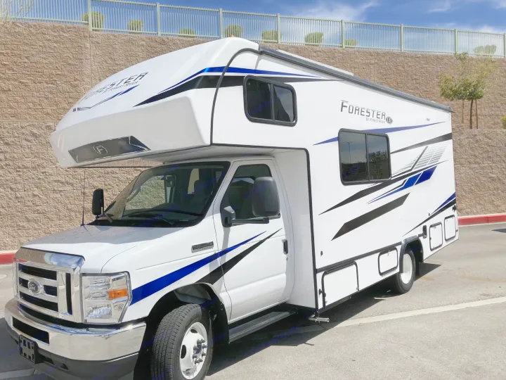 This white Ford E-Series Class C RV, adorned with blue/black graphics, is perfect for your next rv rental. Seen outdoors.. Forester LE 2024