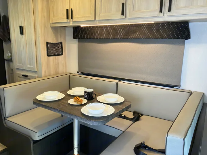 RV rental: A well-lit dinette with light wood cabinets, booth seating, and a set table, perfect for meals on the road.. Forester LE 2024