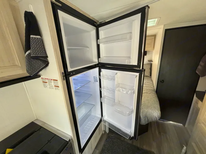 RV rental: Inside a clean, empty two-door refrigerator in a compact camper kitchen, ready for travel.. Forester LE 2024