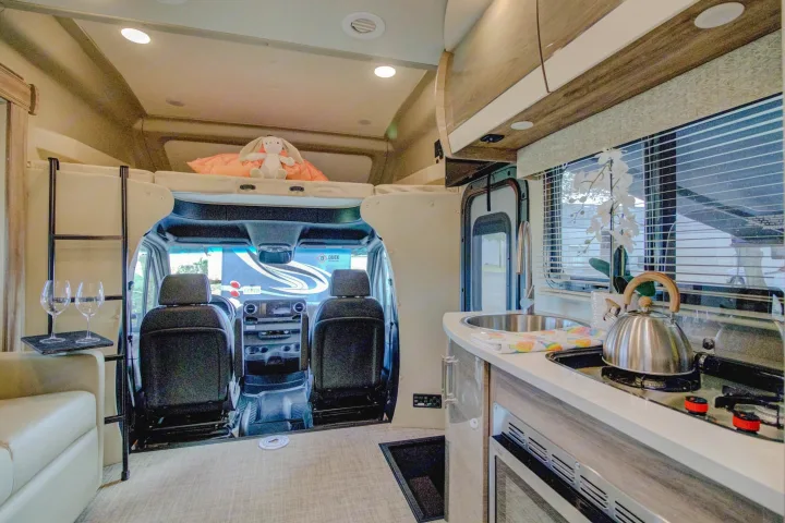 Inside an RV rental: full kitchen, front cockpit, and over-cab bed. Ideal for comfortable travel and family adventures.. Entegra Coach Qwest 2020