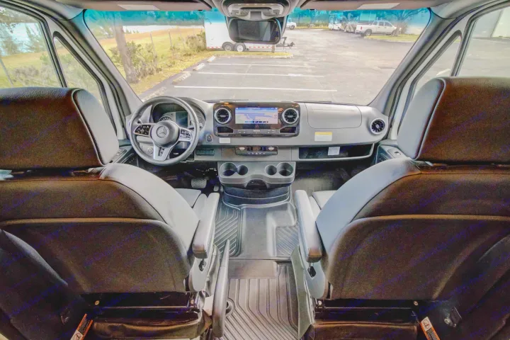 Spacious RV rental interior featuring the driver's cabin, dashboard, navigation screen, and comfortable front seats.. Entegra Coach Qwest 2020