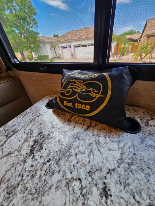 Inside an RV rental, featuring a Jayco pillow on a speckled counter with a clear view outside through the window screen.. Jayco Redhawk 2020