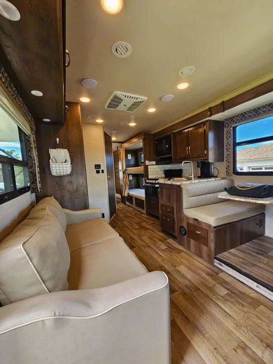 Spacious RV rental interior featuring a living area, kitchenette, dining booth, and bunk beds.. Jayco Redhawk 2020