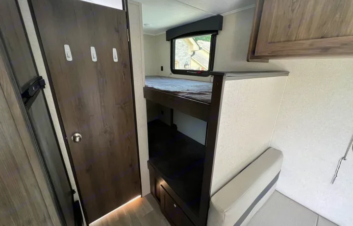 RV rental: Cozy interior showing dark door with hooks, bunk beds, a window, and a light-colored dinette bench with storage.. Clipper Ultra Lite 2022