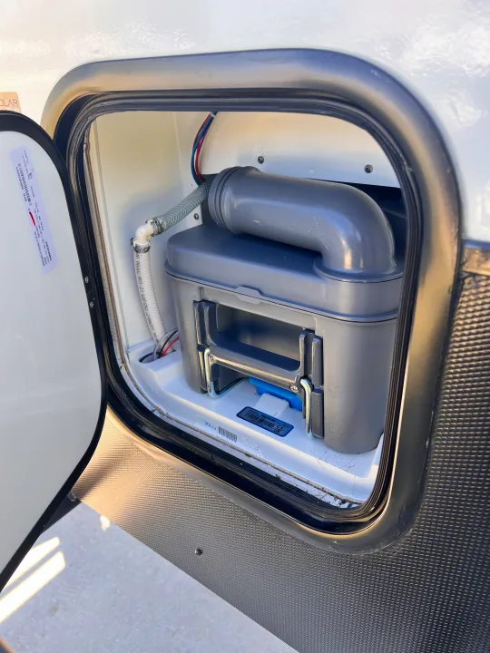 RV rental maintenance: A cassette toilet waste tank is visible in an RV's exterior compartment for easy servicing.. Winnebago Hike 100 2023