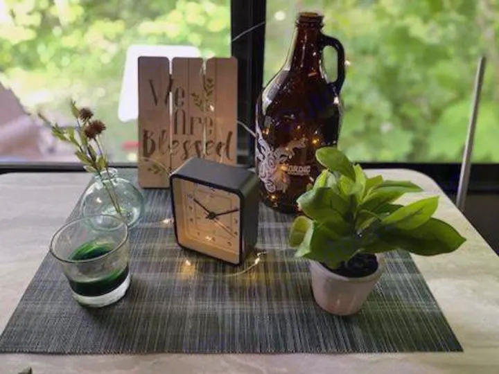 This homey RV rental table features a "We Are Blessed" sign, clock, plants, and string lights, creating a welcoming vibe.. Forest River Wildwood X-Lite 2020