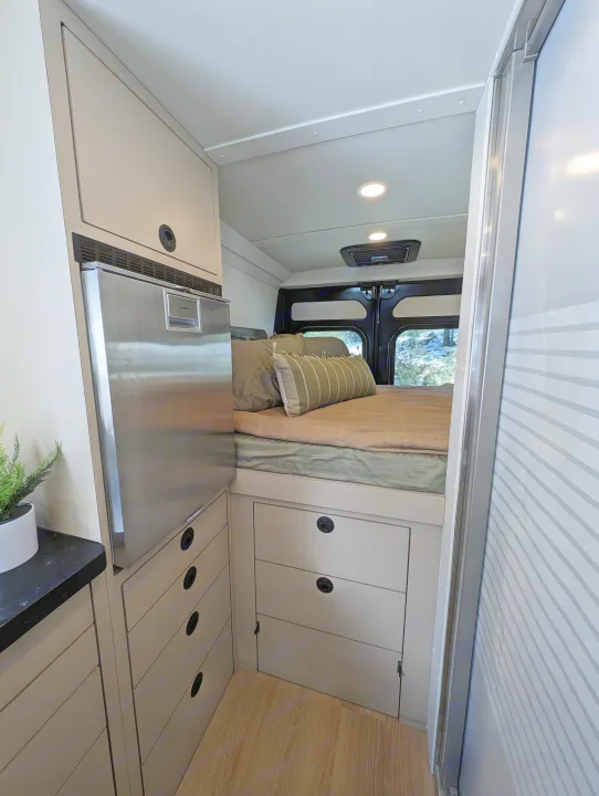 Cozy rv rental interior featuring a comfortable bed, integrated refrigerator, ample storage, and smart design.. New Life Conversions Luxury Edition 2022