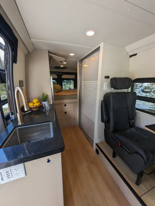 Modern RV rental interior: a compact kitchen with sink, comfy bed, and passenger seating, ready for adventure.. New Life Conversions Luxury Edition 2022