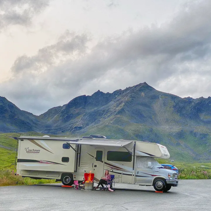 RV rental adventure: Enjoying a campfire by the RV with impressive mountains and a cloudy sky. Perfect outdoor escape.. Forest River Coachmen Freelander 2015