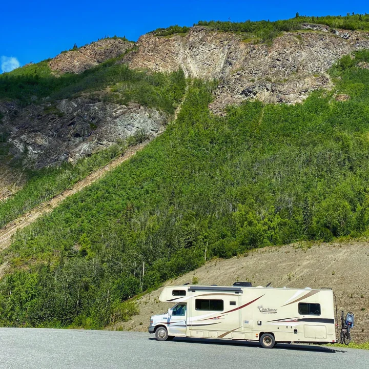 Coachmen RV rental parked by a rocky, green mountain. Perfect for a nature road trip.. Forest River Coachmen Freelander 2015
