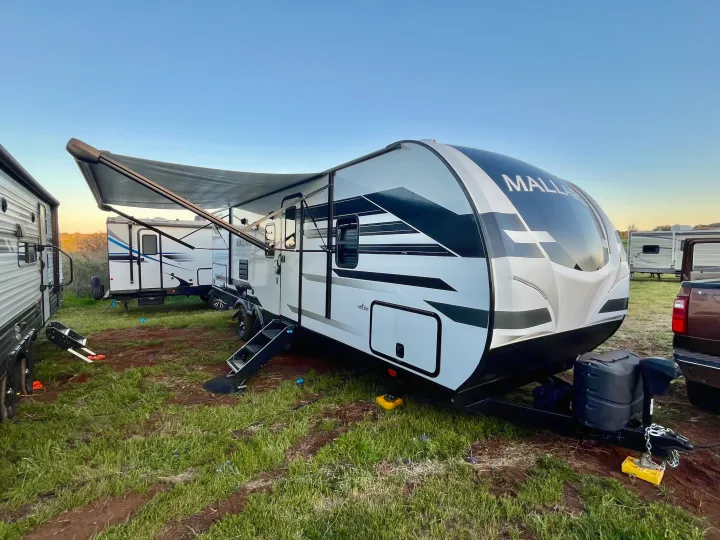 Mallard RV rental set up with an extended awning in a grassy outdoor campsite, ready for adventure and travel.. Heartland M-3385 2021
