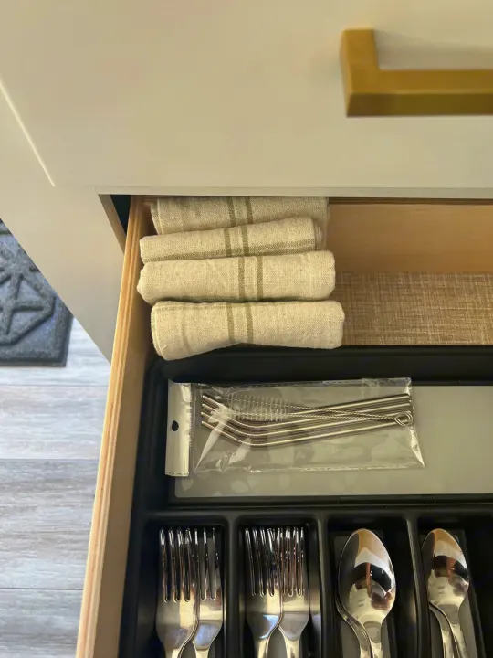 An organized kitchen drawer in an RV rental reveals folded dish towels, reusable straws, and shiny silverware, ensuring convenience.. Jayco 224BHW 2024