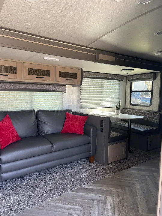 RV rental interior: A comfy dark sofa with red pillows and a stylish dinette with patterned seating. Bright and modern living space.. Shadow Trailers Shadow Cruiser 2020