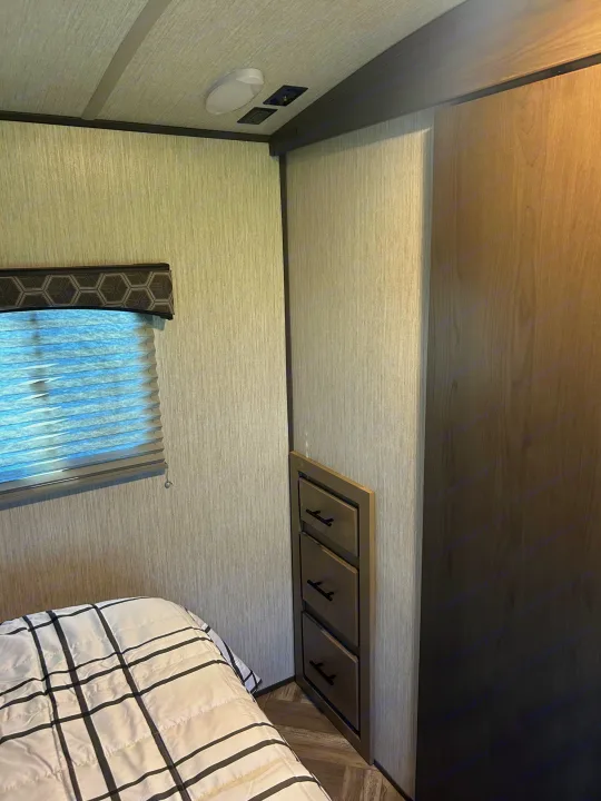 Cozy RV rental bedroom: features a plush bed, window blind, built-in storage, power outlets, and light-textured walls.. Shadow Trailers Shadow Cruiser 2020