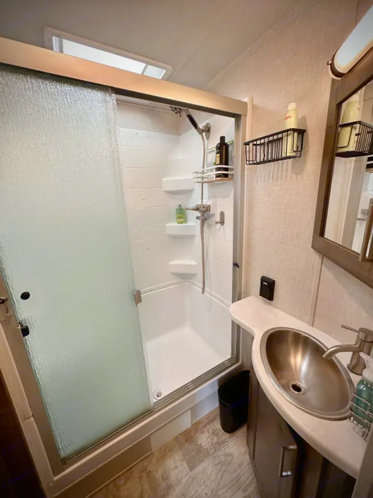 Modern RV rental bathroom features a glass shower, sleek sink, and essential toiletries, ideal for comfortable travel.. Forest River Flagstaff Classic 2022