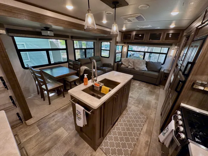 Modern RV rental interior: kitchen island, dining, & living space. Enjoy comfort in this well-appointed camper.. Forest River Flagstaff Classic 2022