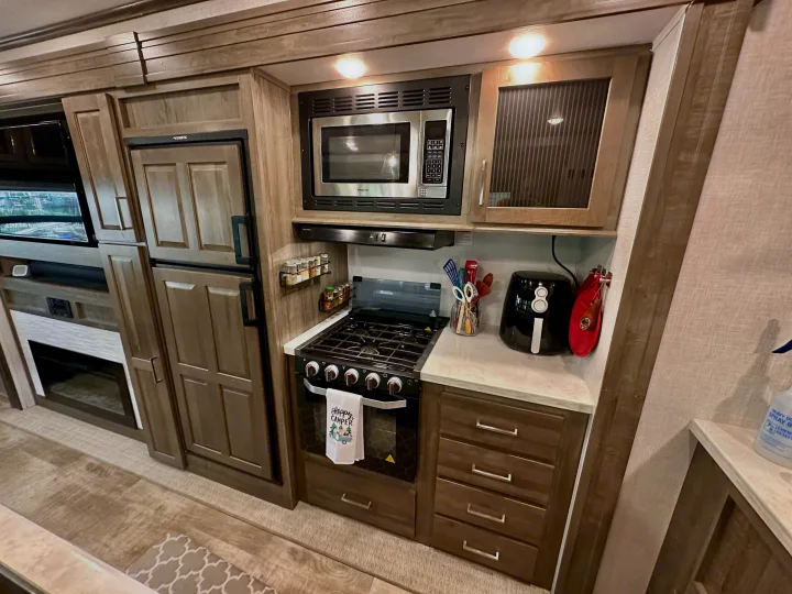 RV rental interior: well-appointed kitchen (stove, microwave, fridge, air fryer) & living area with TV/fireplace.. Forest River Flagstaff Classic 2022