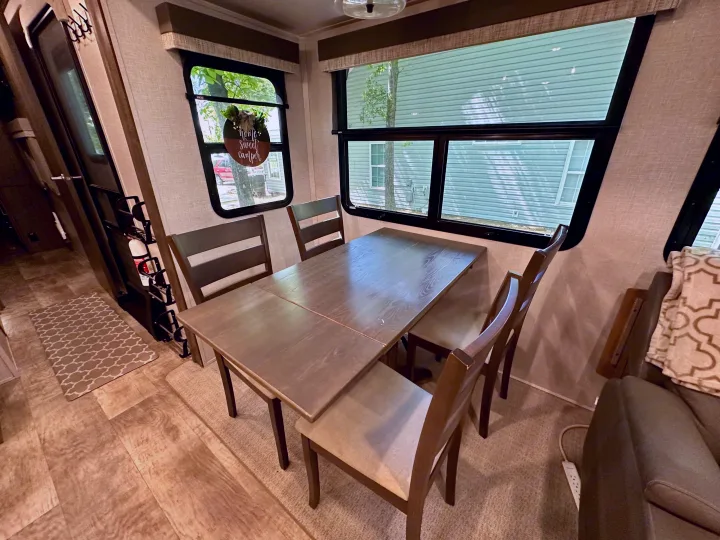 Modern RV rental dining area with a wood table, chairs, and large windows offering an exterior view.. Forest River Flagstaff Classic 2022