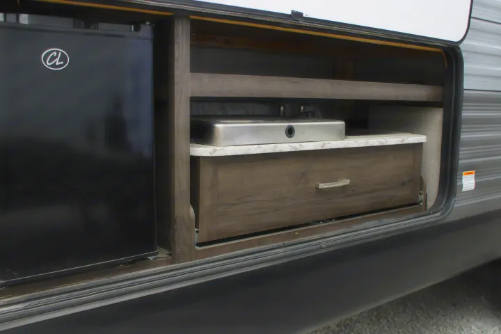 An RV rental outdoor kitchen, featuring a compact fridge, integrated sink/stove, and a pull-out drawer.. Jayco Jayflight SLX 8 2021
