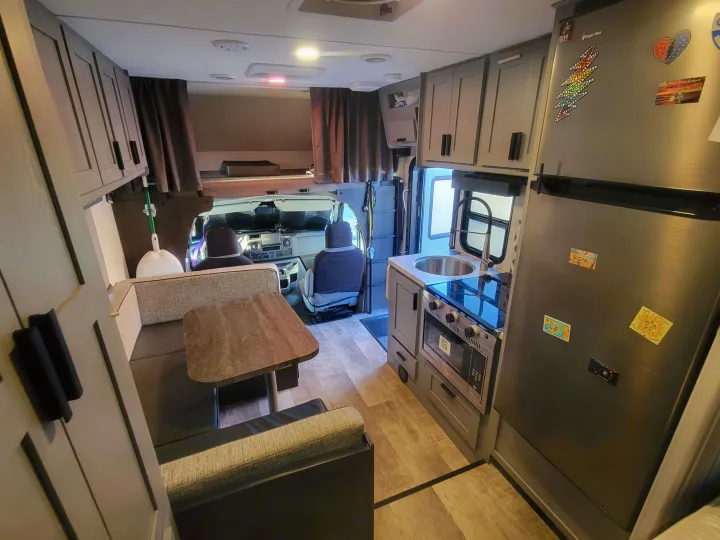 This RV rental interior features a well-equipped kitchenette, dinette, overhead bunk, and cab for travel.. Solera Solera Motorhome 2022