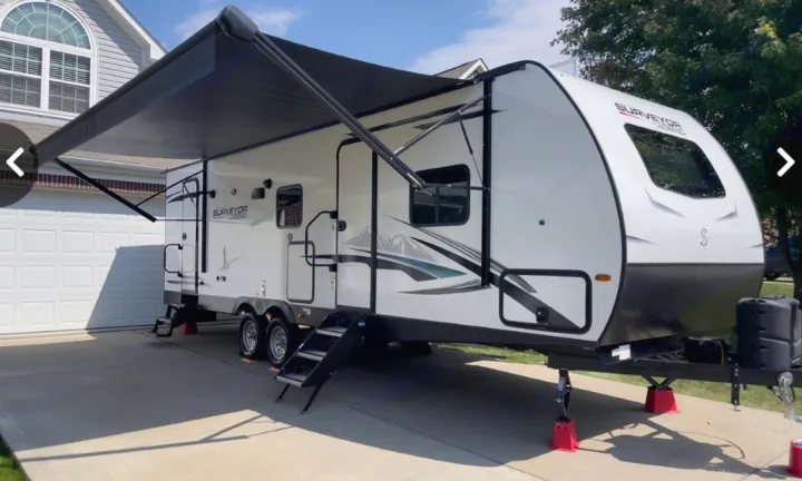 This white Surveyor Legend RV rental, with an extended awning, is parked on a sunny driveway, ready for adventure.. Forest River Surveyor Legend 2022