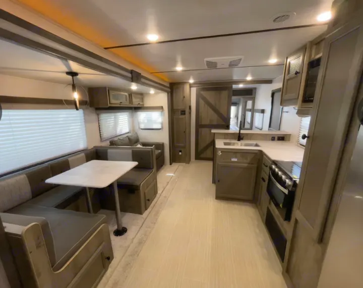 Modern RV rental interior with full kitchen, U-shaped dining booth, and ample living space.. Forest River Surveyor Legend 2022